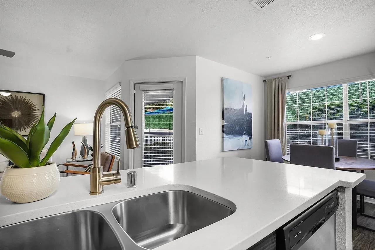 Kitchen island with sink and faucet, looking into living room and dining area at La Ventana, offering apartments in Albuquerque, NM.