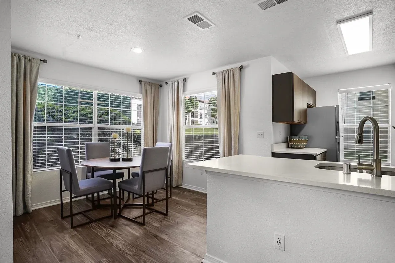 Dining area with table and chairs next to kitchen counter and refrigerator at La Ventana, offering apartments in Albuquerque, NM.