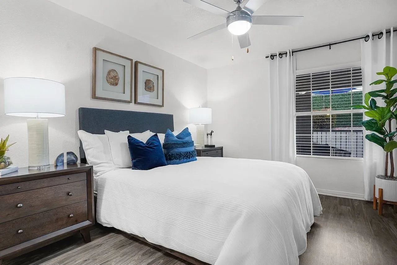 A bedroom with a king-size bed, nightstands, and a ceiling fan at La Ventana, offering apartments in Albuquerque, NM.