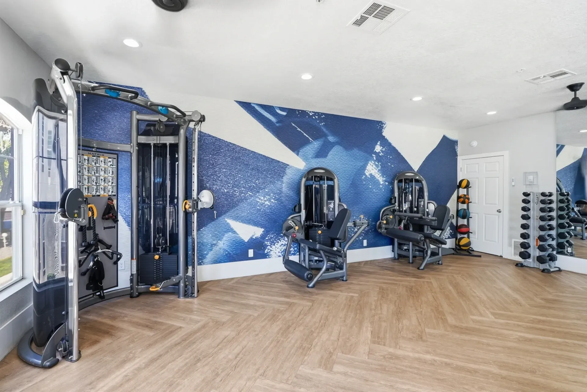 Gym with cable machines, leg press machine, and dumbbell rack at La Ventana, offering apartments in Albuquerque, NM.
