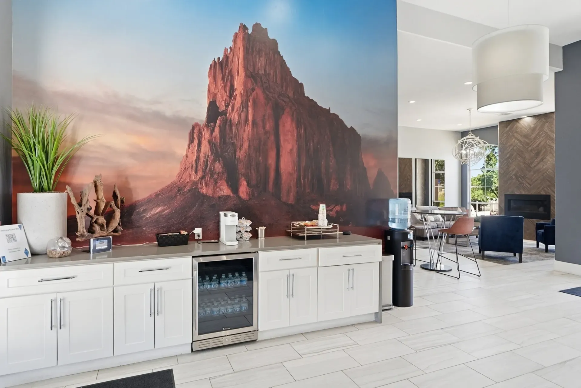 Community room with a large mountain mural, coffee station, and water cooler at La Ventana, offering apartments in Albuquerque, NM.