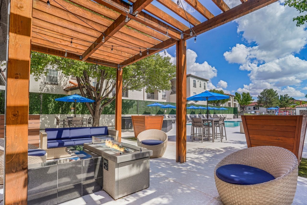 Outdoor communal courtyard with a pergola, fire pit, and poolside seating.