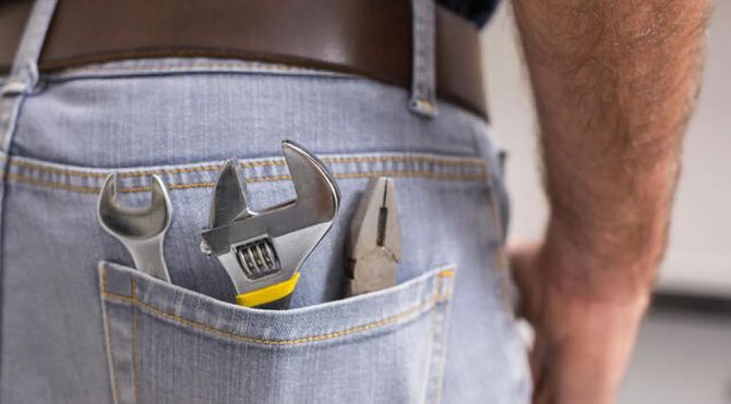Tools in a back pocket of blue jeans on a worker standing indoors