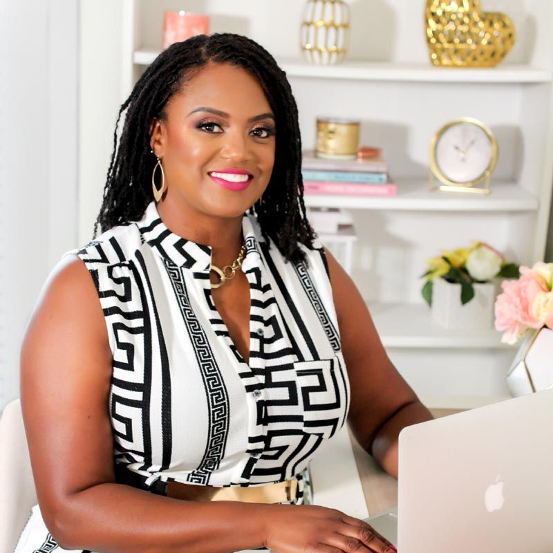 Dr. Franchelle Caesar, The Life Coach for High-Achieving Women, smiling at a desk with gold accessories in the background