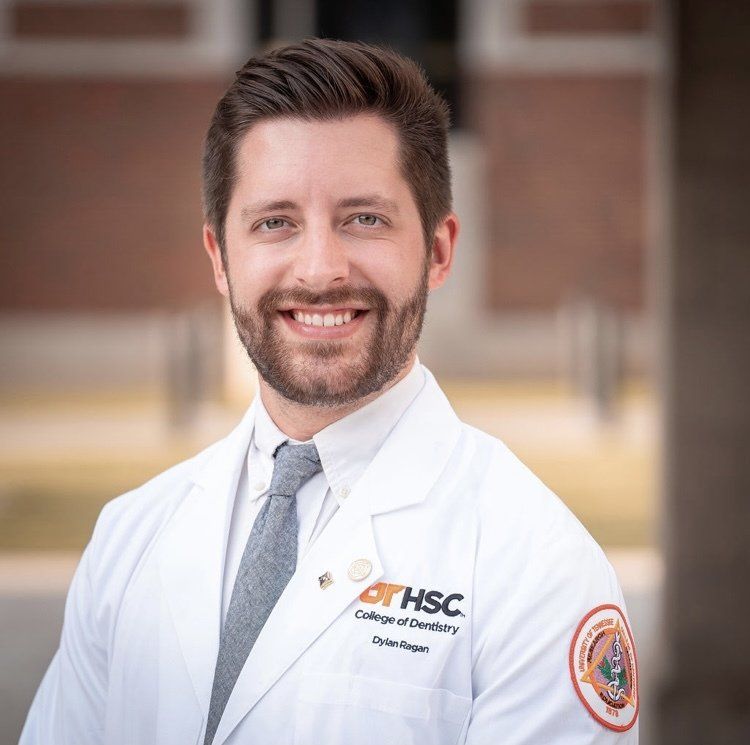 A man with a beard wearing a white lab coat and tie