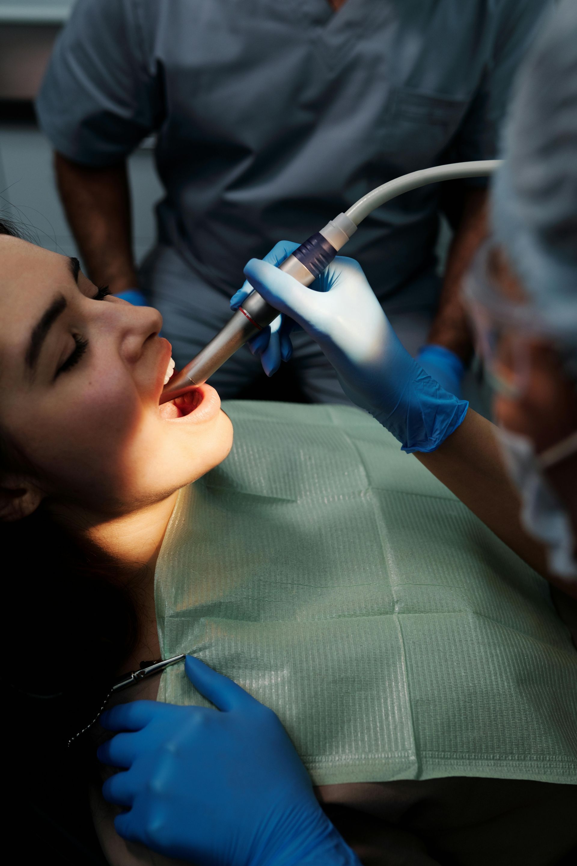 A woman is getting her teeth examined by a dentist in a dental office.