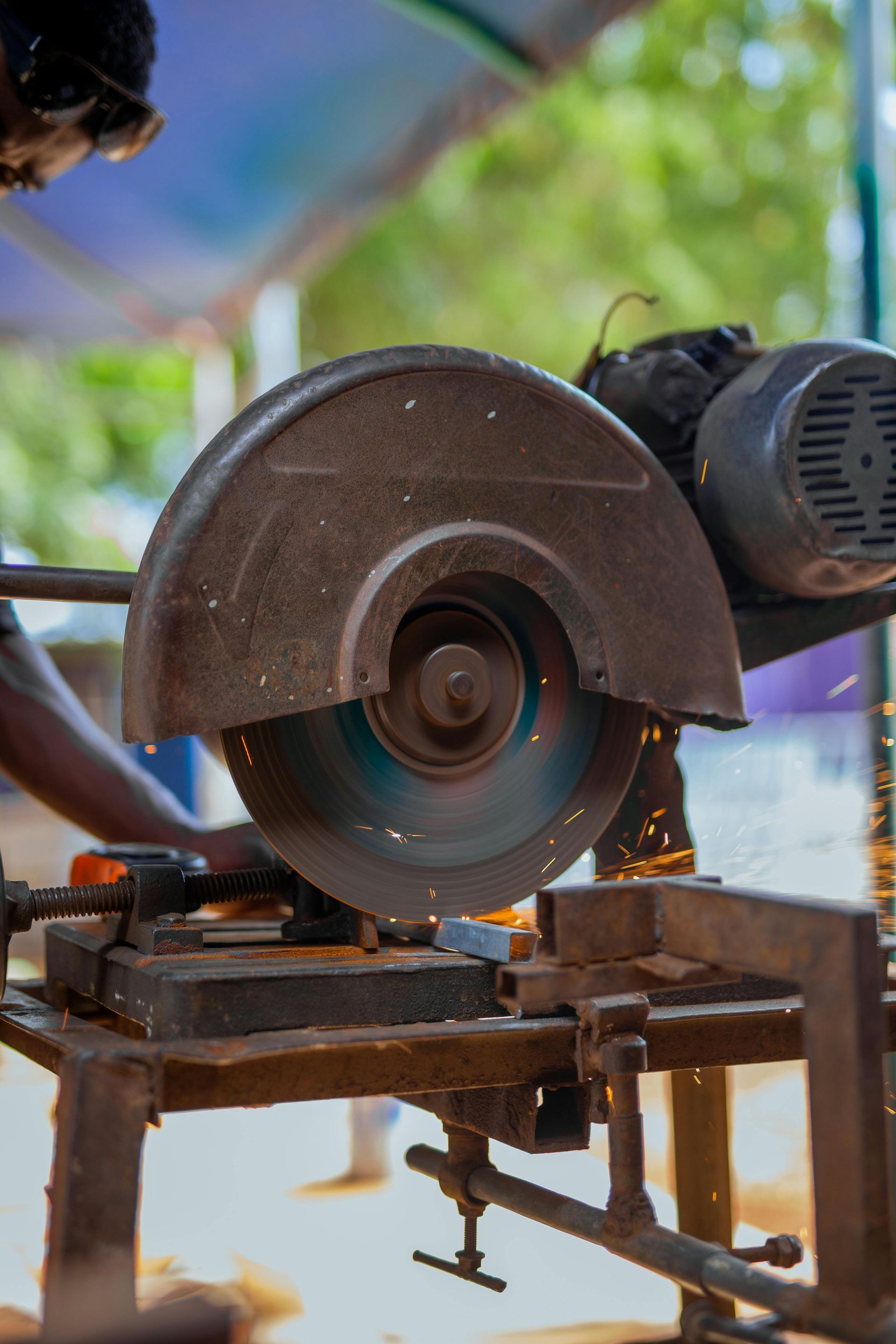 Saw cutting metal, sparks flying. A person uses an electric saw outdoors.