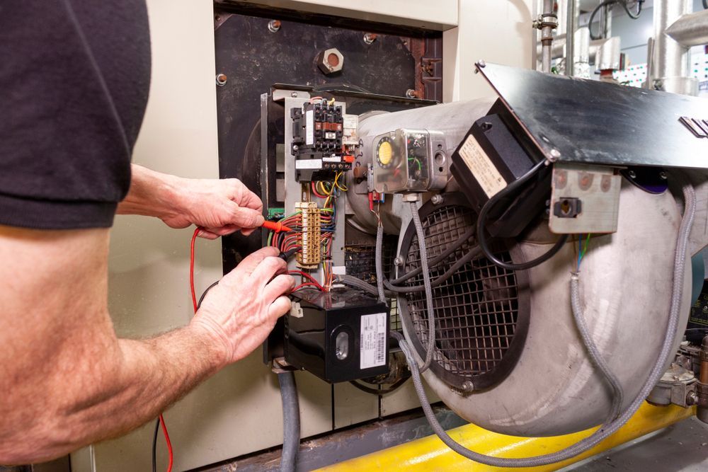 Person tests electrical components on industrial machinery.