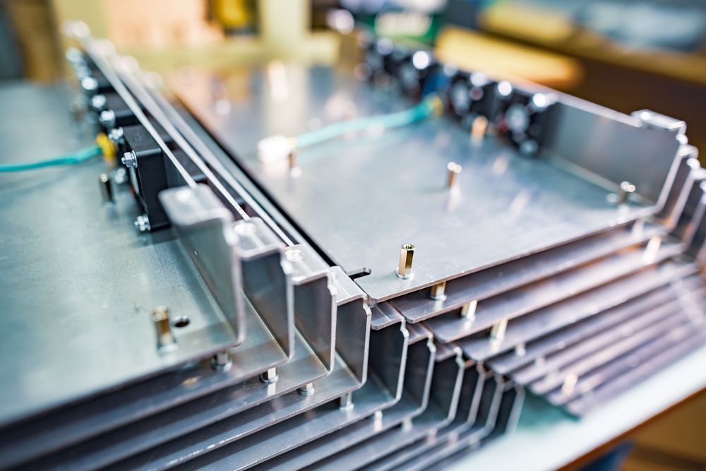 Stack of metal electronic components, likely for cooling or power. Silver, with fins and fans visible.