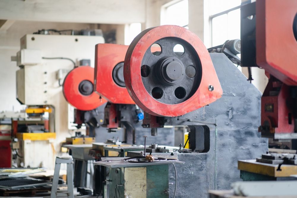 Red and gray industrial stamping machines in a factory setting.
