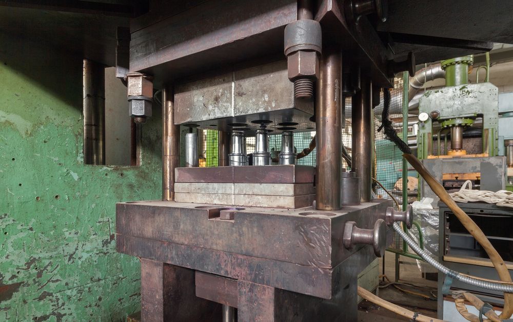 Industrial metal press machine in a factory setting.