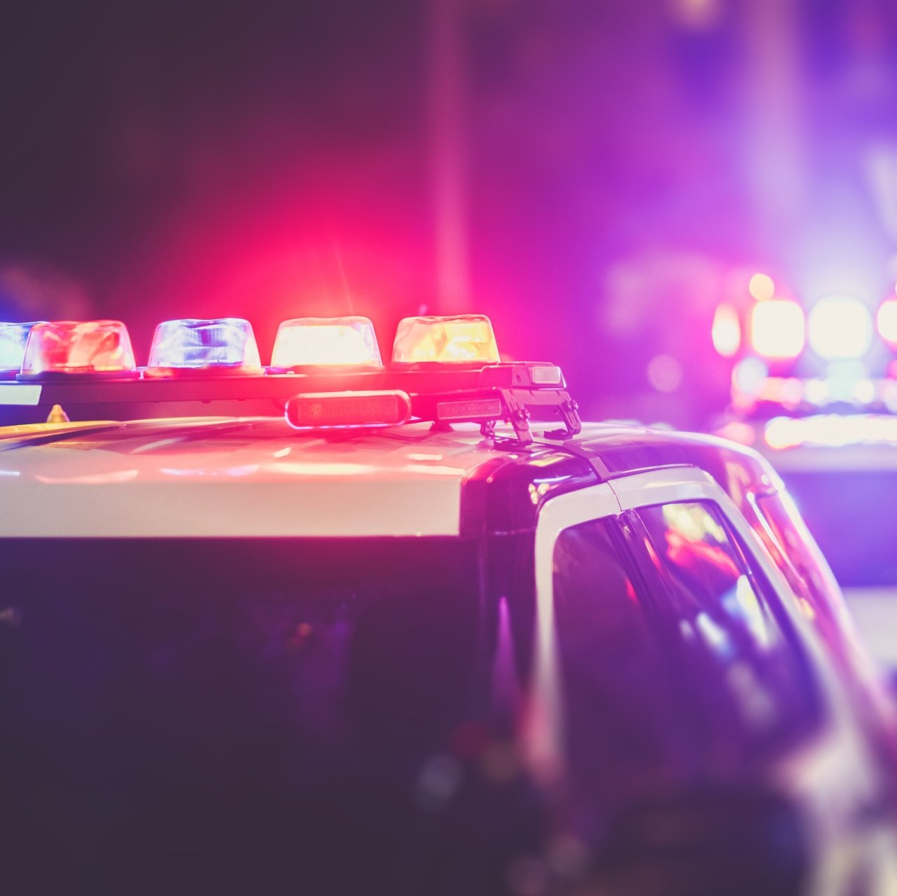 A police car with red and purple lights on top of it.