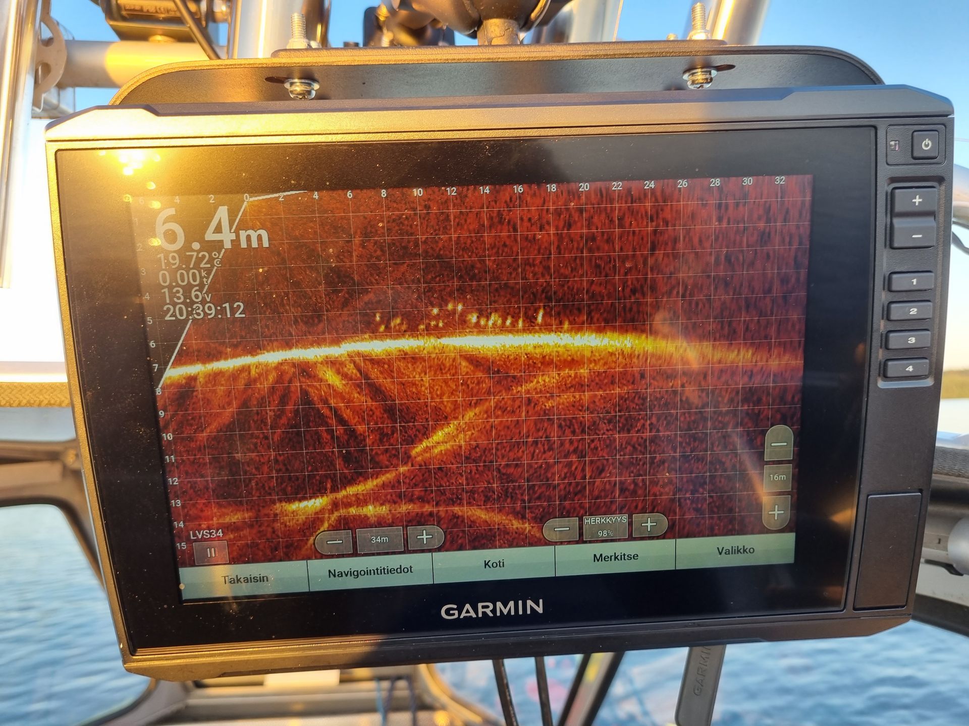 Garmin fishfinder display showing live sonar scan with school of pikeperch at sunset on a boat