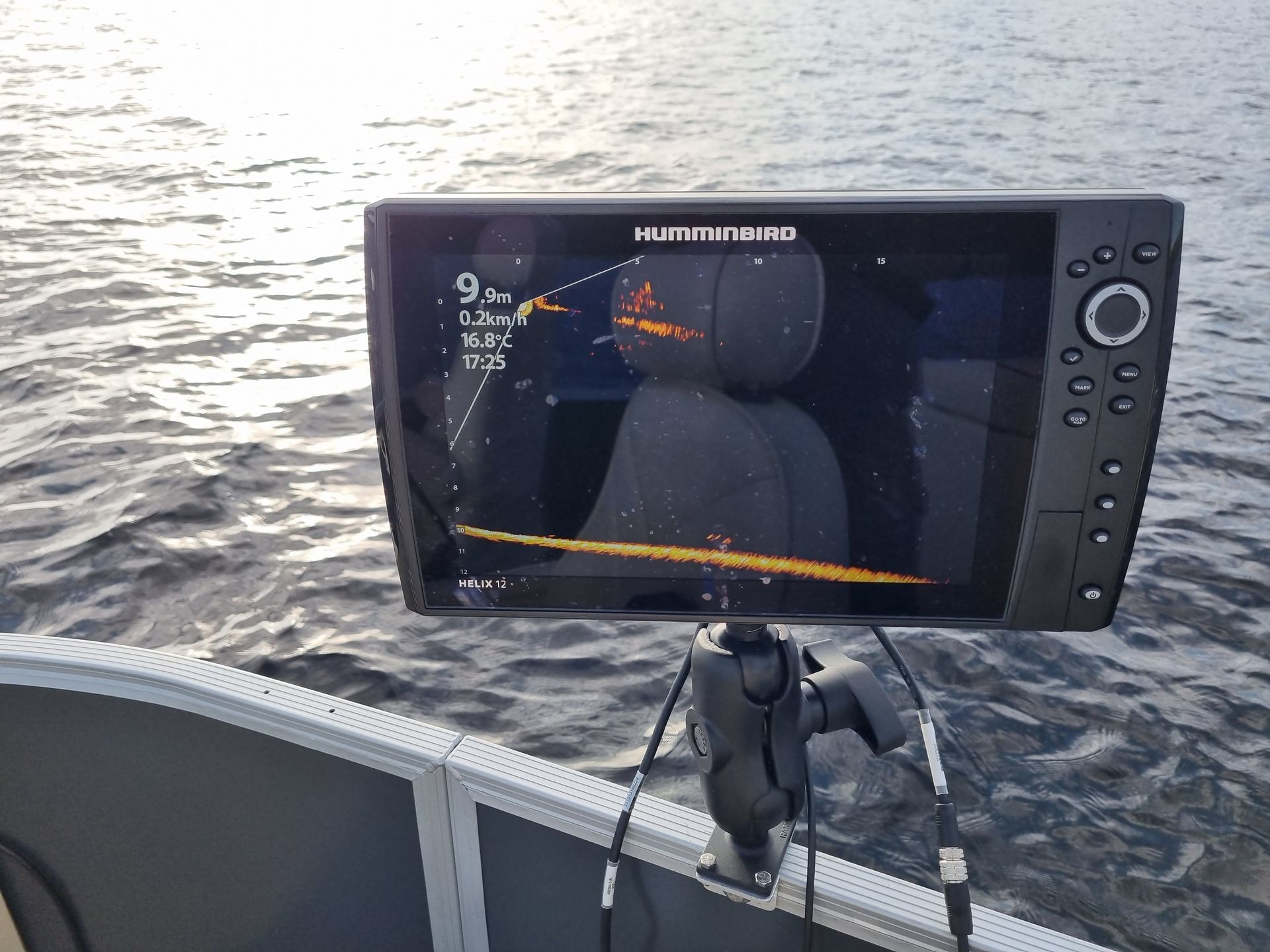 Boat-mounted fish finder display over rippling water, showing live sonar view at the stern.