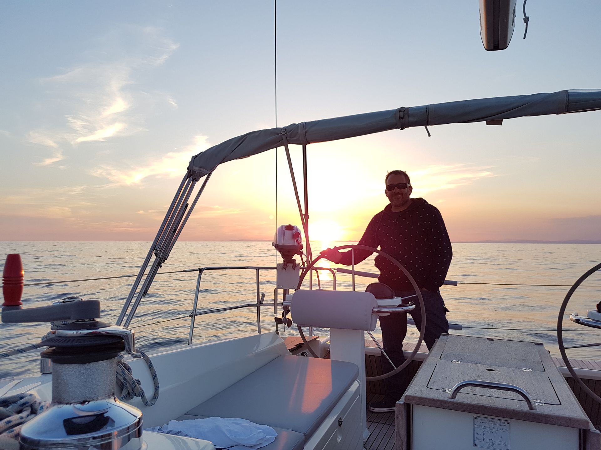 Un hombre está conduciendo un barco en el océano al atardecer.
