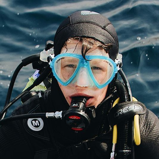 Un niño pequeño que lleva un equipo de buceo con la letra m.