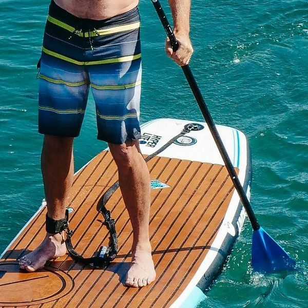 Un hombre está de pie sobre una tabla de remo en el agua.