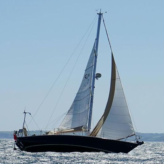Un velero negro con velas blancas en el océano