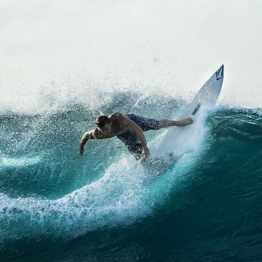 Un hombre está montando una ola en una tabla de surf en el océano.