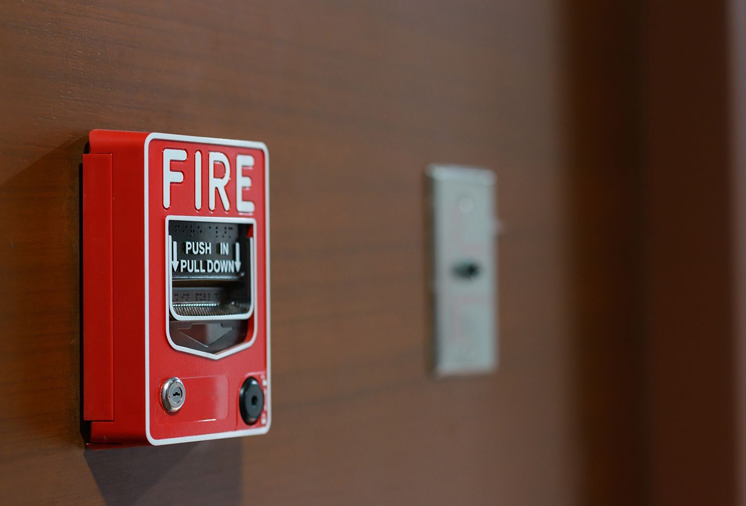 Red fire alarm pull station mounted on a wall for emergency activation. Red fire alarm pull station mounted on a wall for emergency activation.