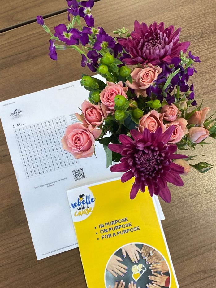 Pink and purple flower bouquet on a desk beside a calendar and yellow notebook