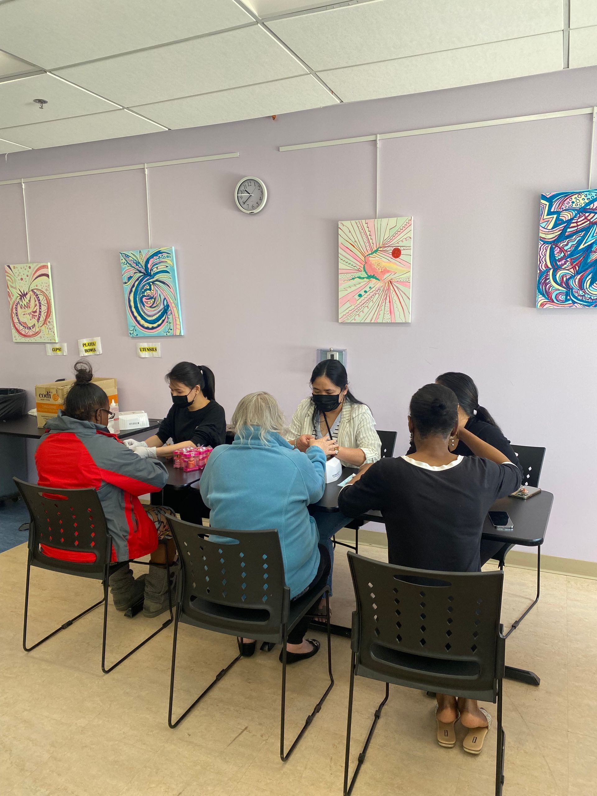 People seated around a table in a bright room with colorful wall art, engaged in a group activity.