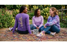 Three people sitting cross-legged surrounded by broken crayons, smiling and talking in a garden.