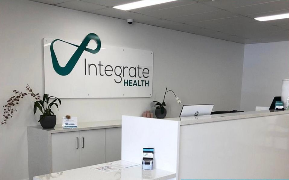 Two Women at a Reception Desk, With Integrate Health Sign — Integrate Health In Ooralea, QLD