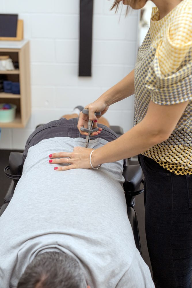 Chiropractor Adjusting A Patient's Lower Back Using An Activator Tool — Integrate Health In Ooralea, QLD