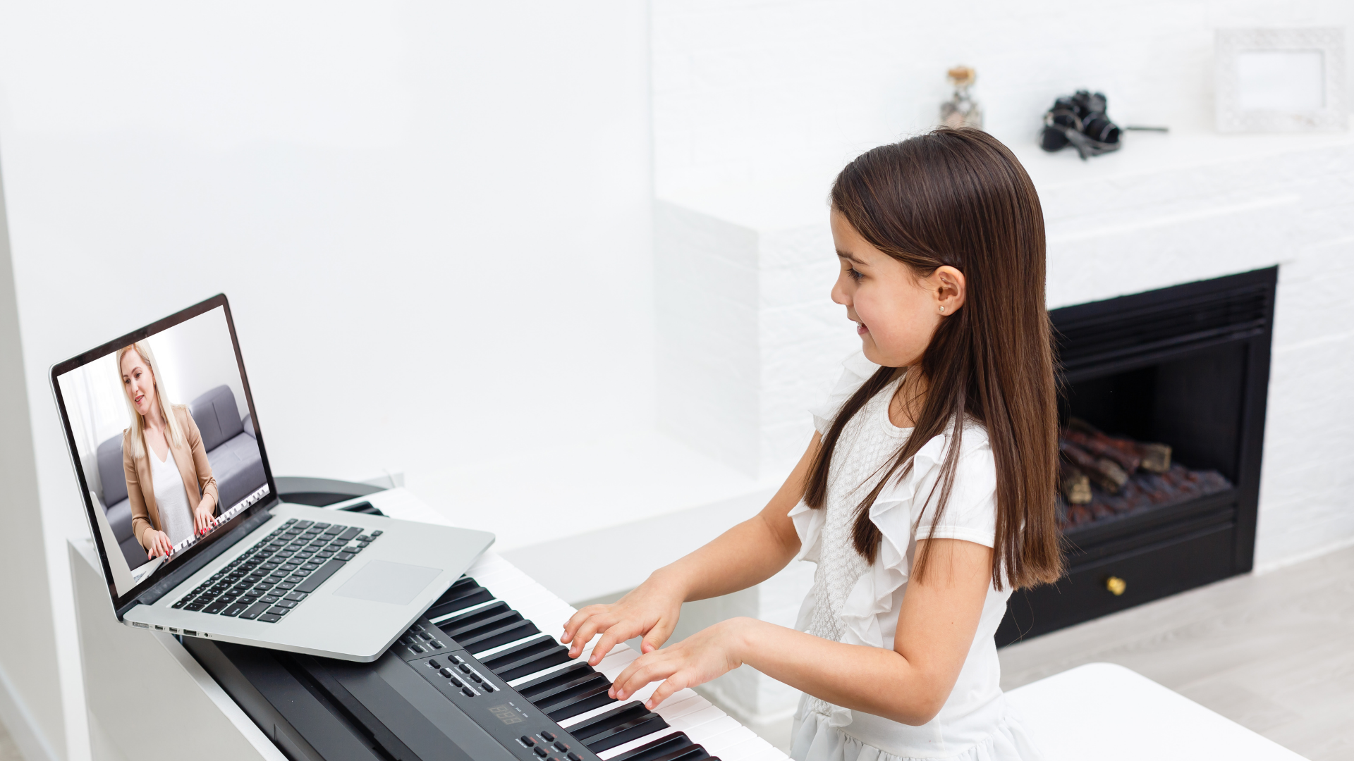 Child playing keyboard with a laptop video lesson in a bright living room