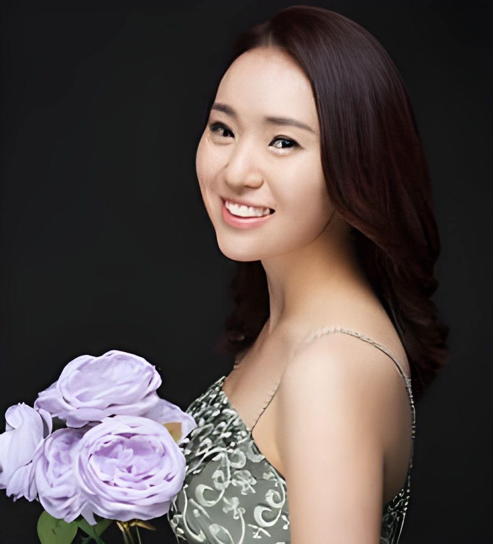 Smiling woman holding a bouquet of lavender roses against a dark background