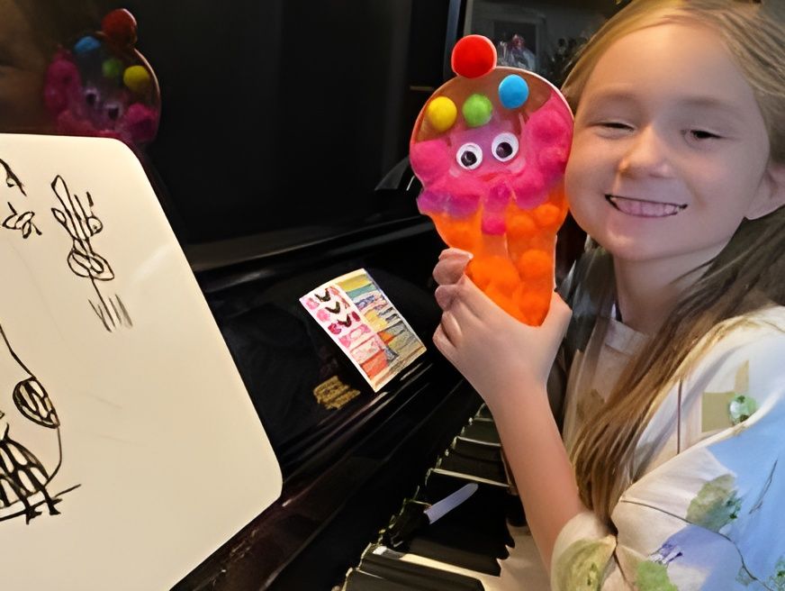 Smiling child holding a colorful plush toy beside a piano and whiteboard