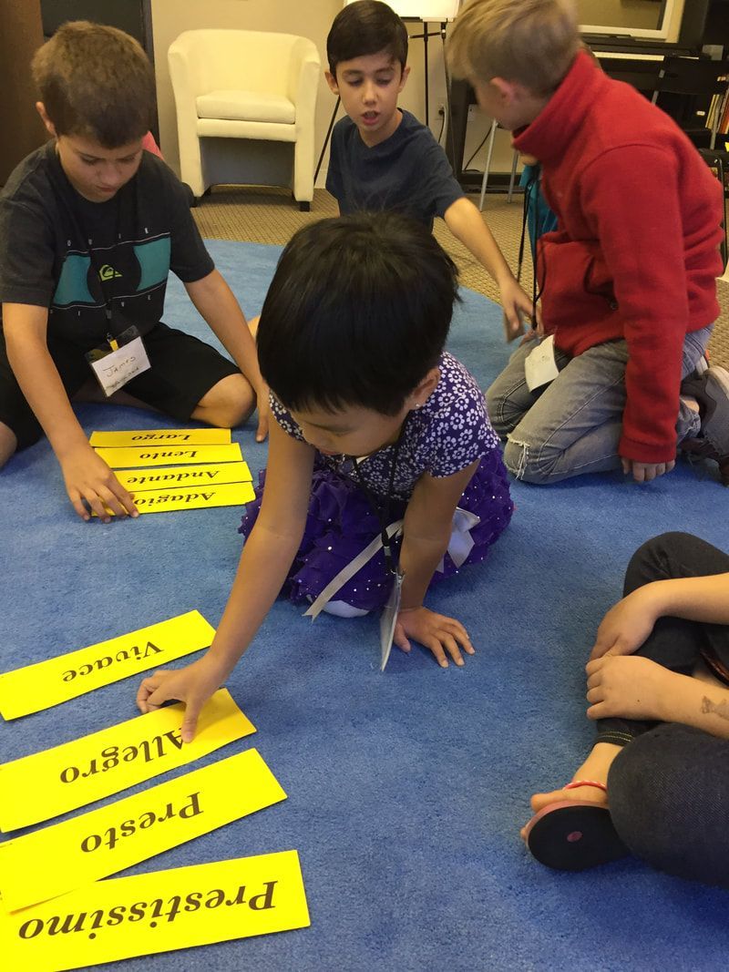 Children in a classroom sorting yellow word cards on a blue carpet