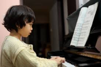 Child playing piano with sheet music on the stand