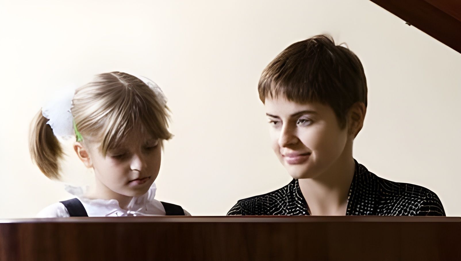 Two people seated side by side, looking down and smiling softly over a wooden surface.