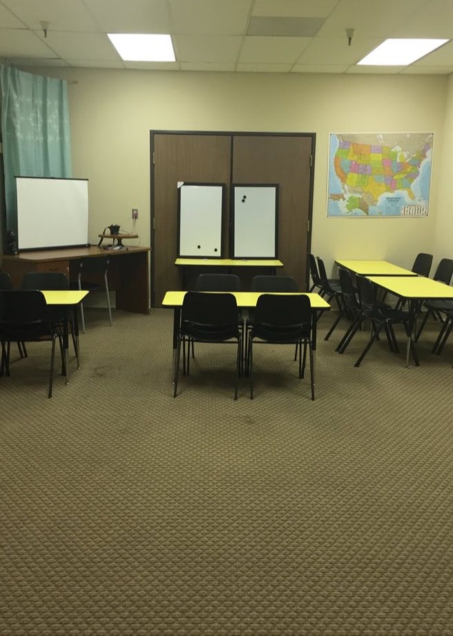 Empty classroom with desks, chairs, whiteboard, and world map on the wall.