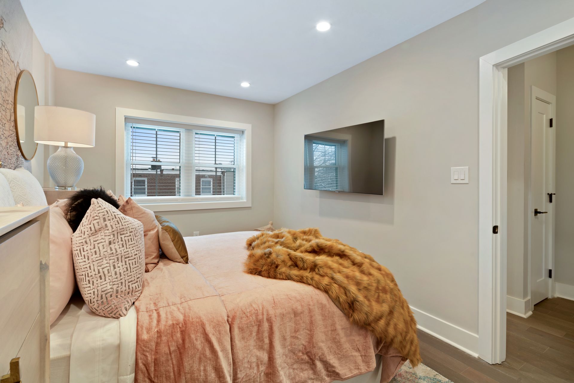 A woman is sleeping on a bed in a bedroom with a television on the wall.