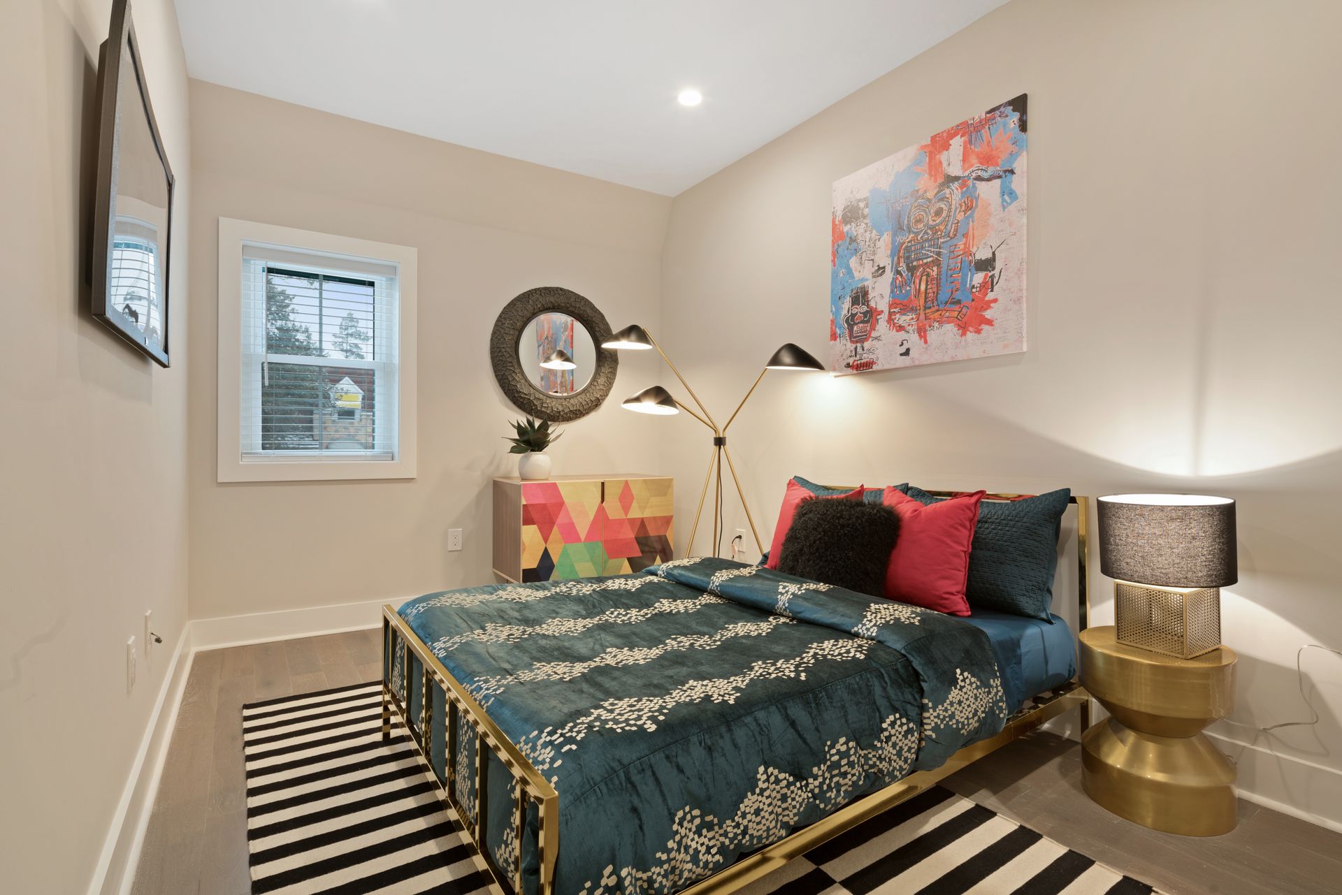 A bedroom with a bed , lamps , a rug and a painting on the wall.