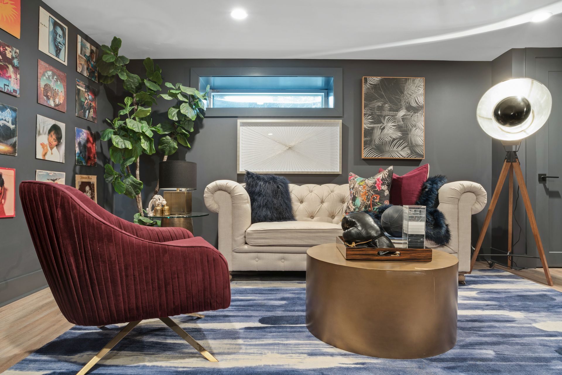 A living room with a couch , chair , coffee table and lamp.
