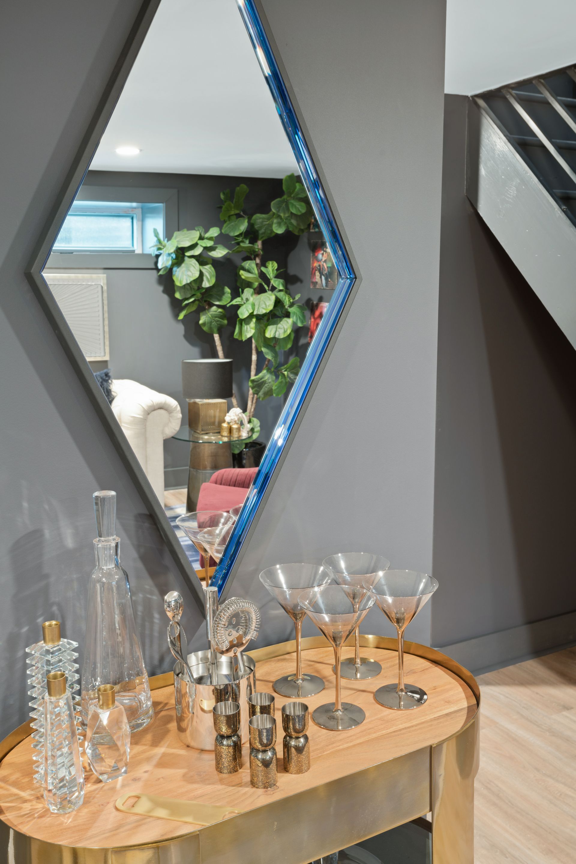 A bar with a mirror and glasses on it in a living room.
