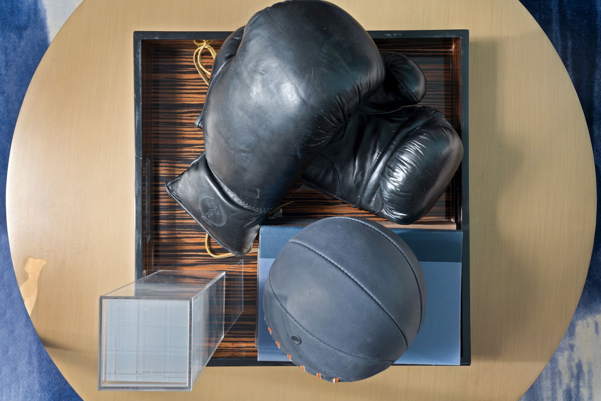 A pair of boxing gloves and a basketball are on a table.