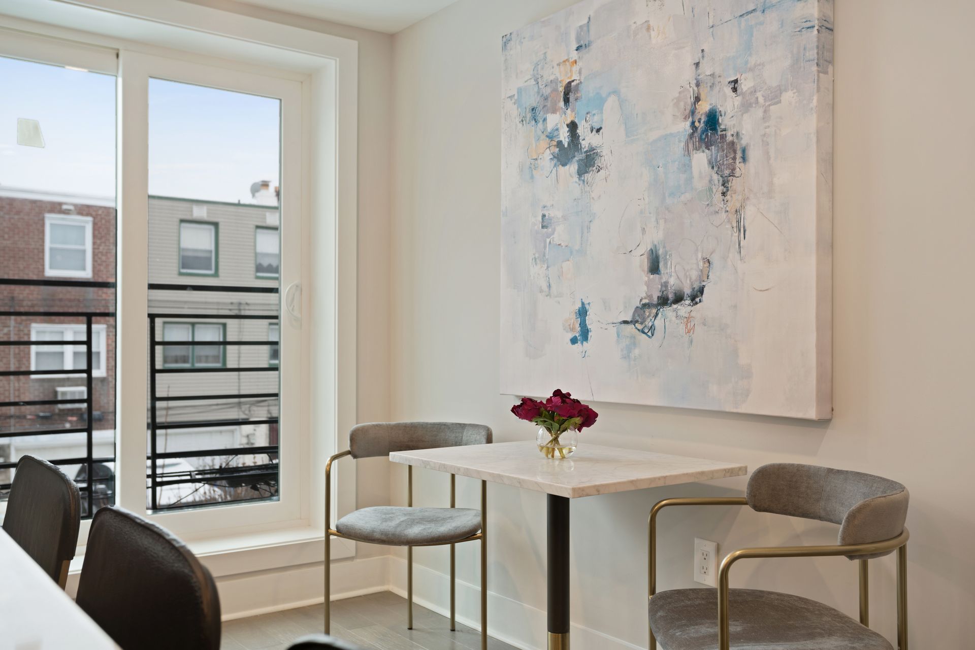 A dining room with a table and chairs and a painting on the wall.