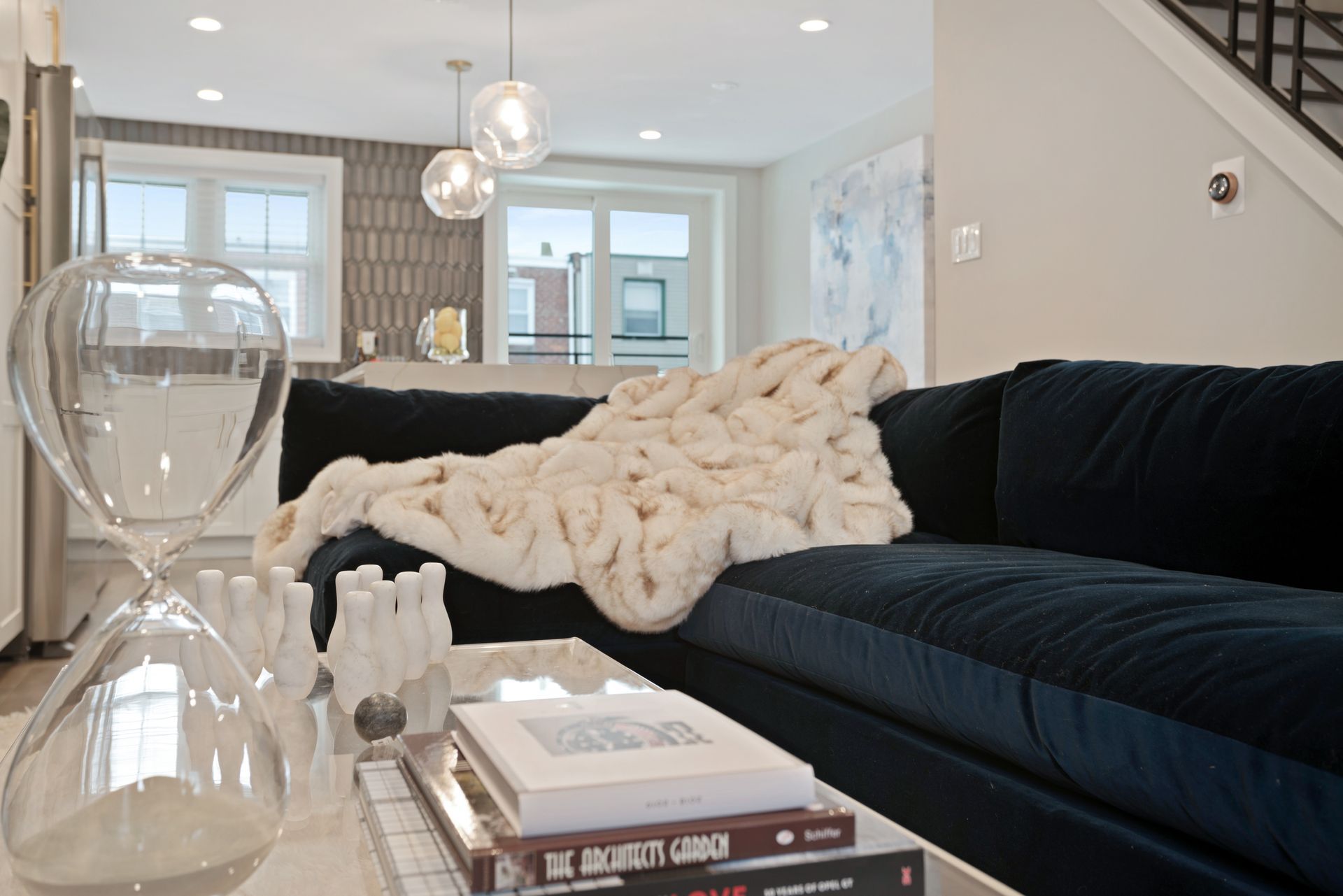 A living room with a black couch and a stack of books on a coffee table
