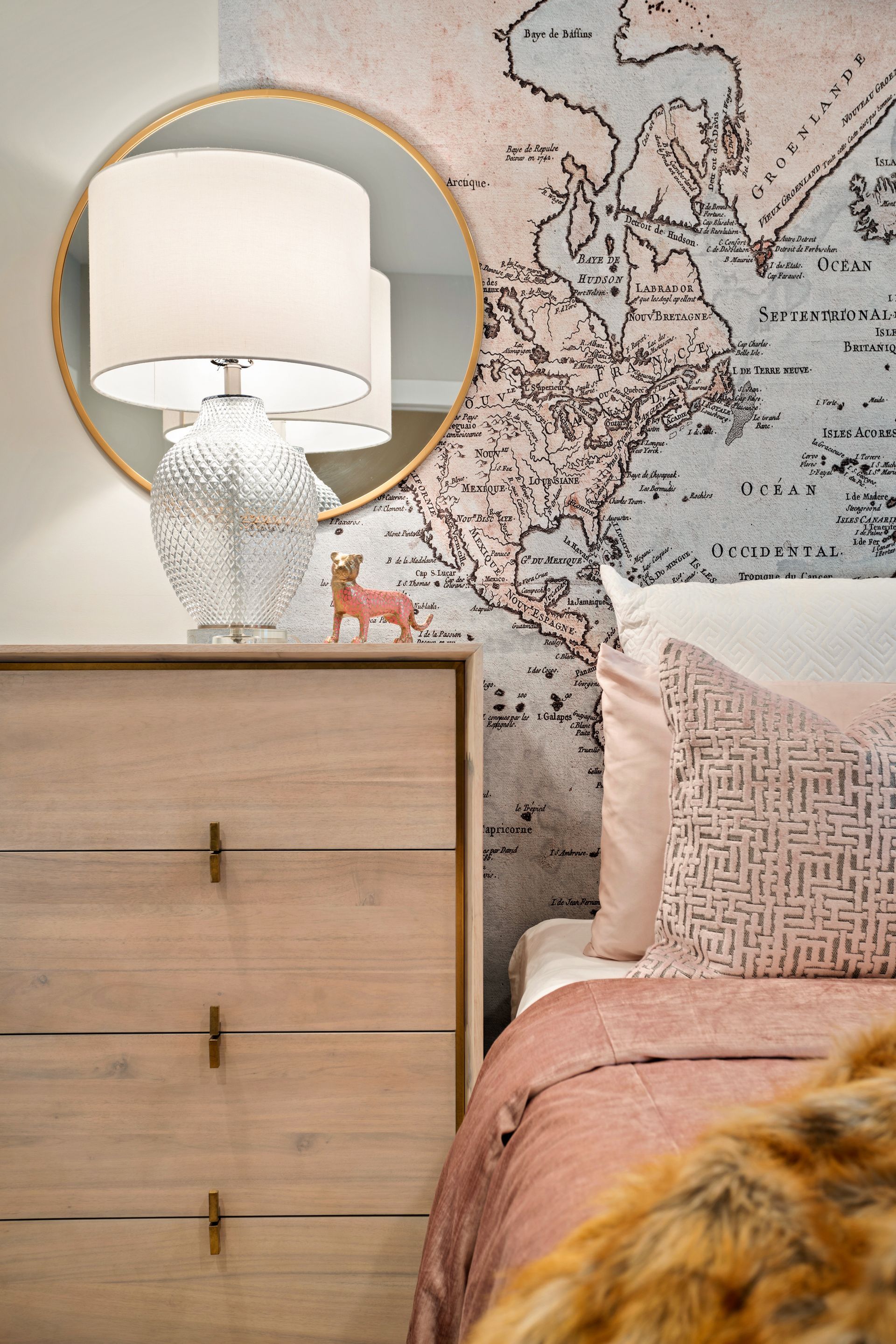 A bedroom with a bed , dresser , lamp and mirror.