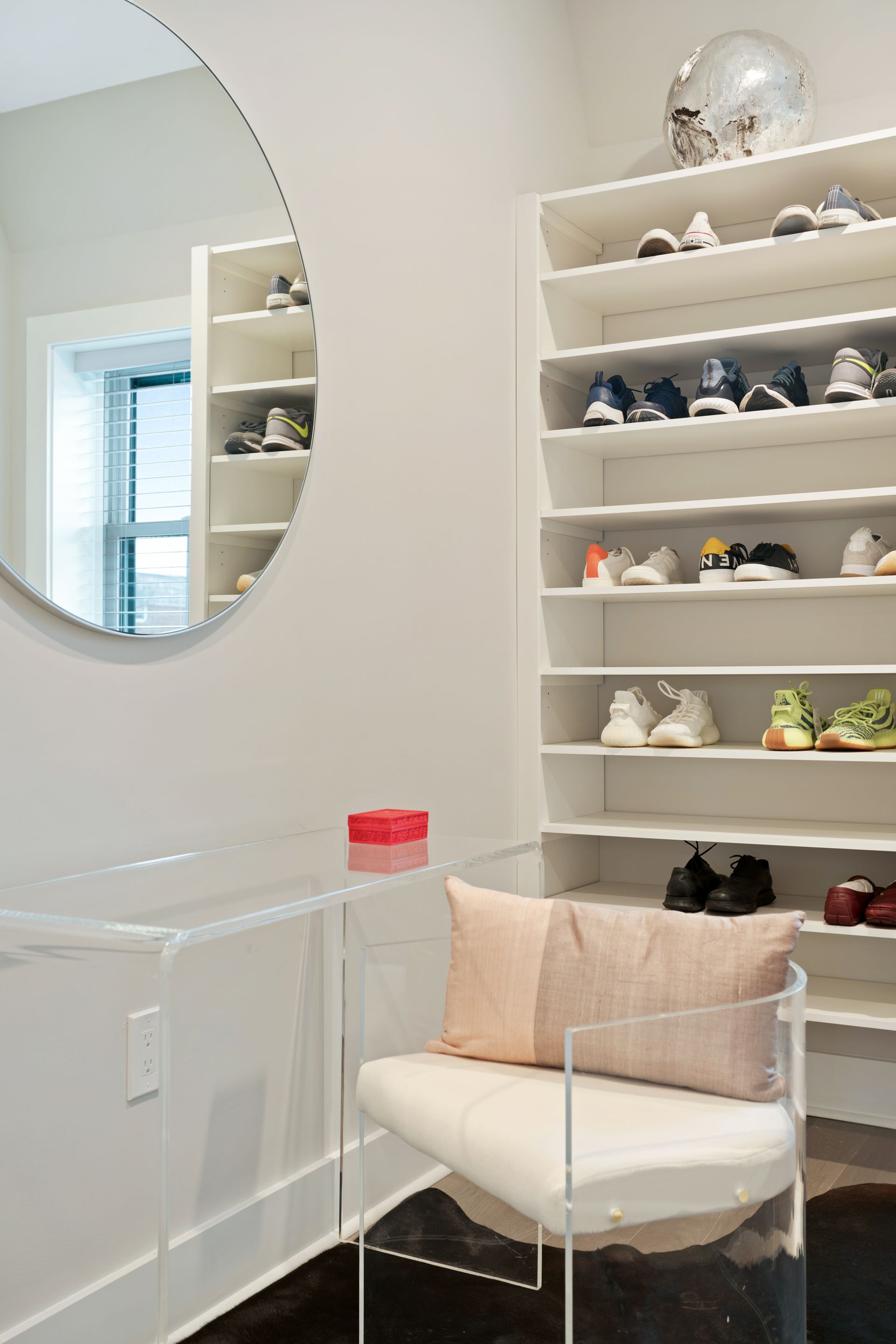A closet with a chair , mirror , and shelves filled with shoes.