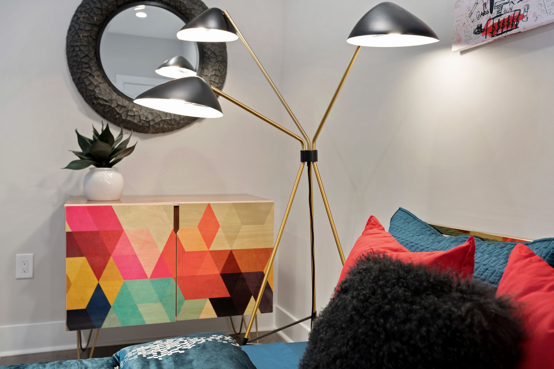 A living room with a colorful cabinet and a lamp