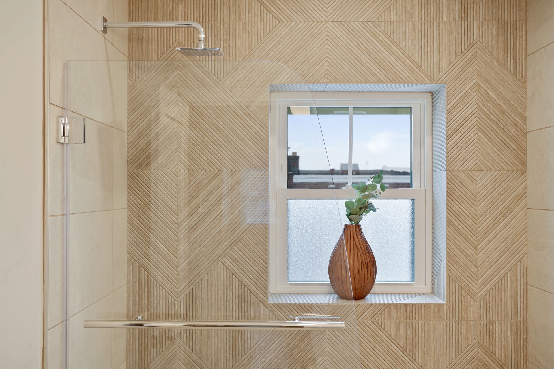 A bathroom with a shower and a window with a vase on the window sill.