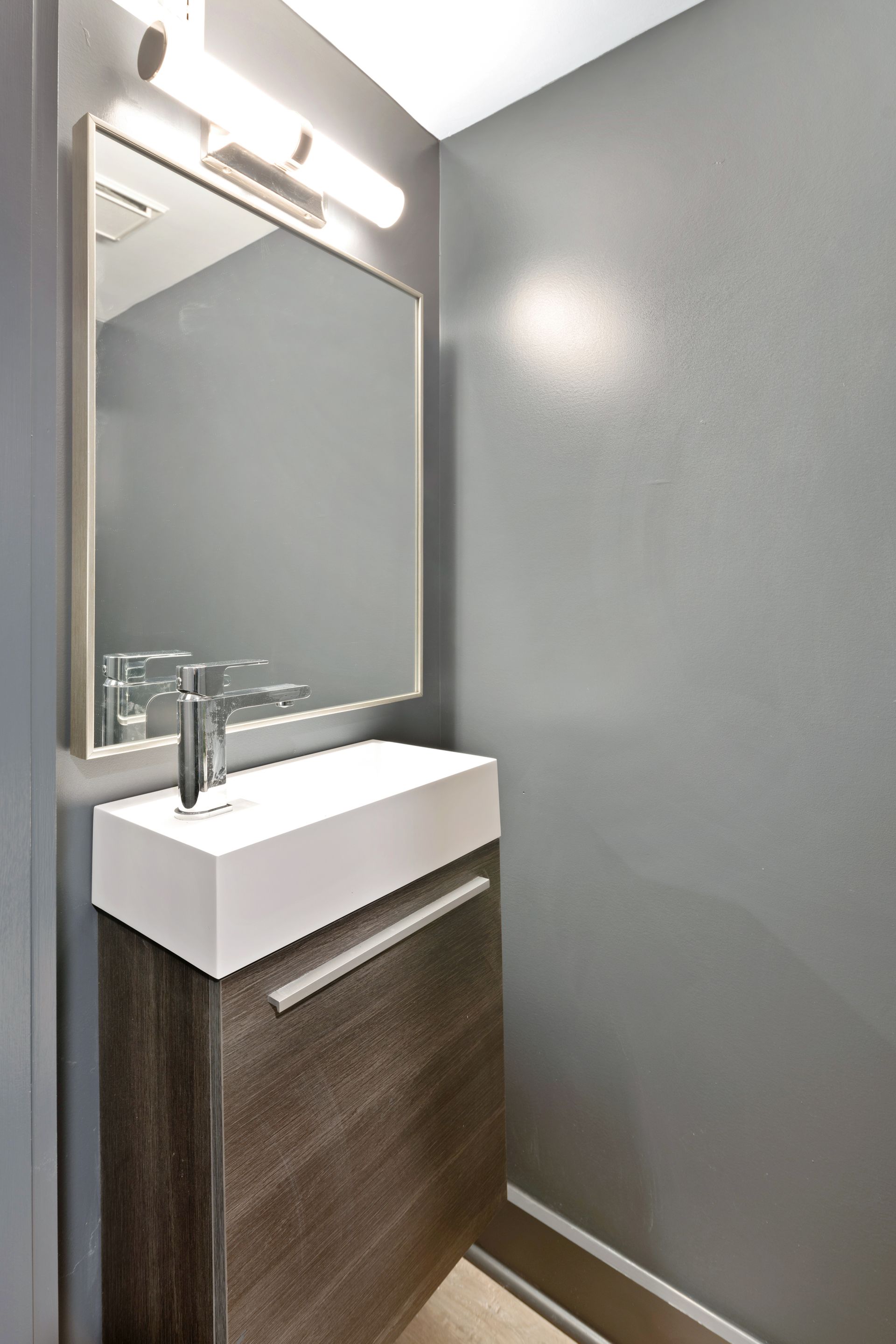 A bathroom with a sink , mirror and light.