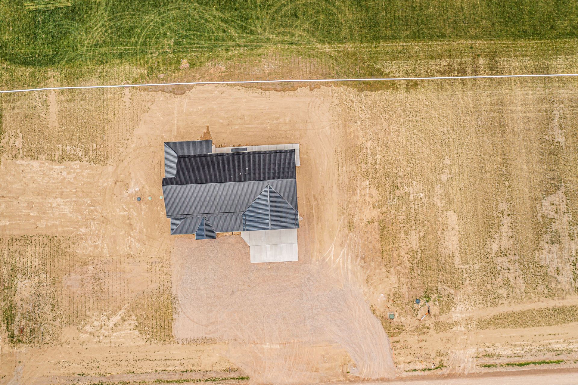 An aerial view of a house in the middle of a dirt field.