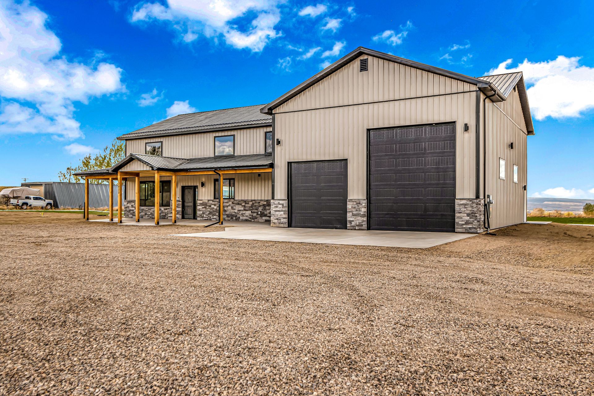 A large house with two garage doors is sitting on top of a dirt field.